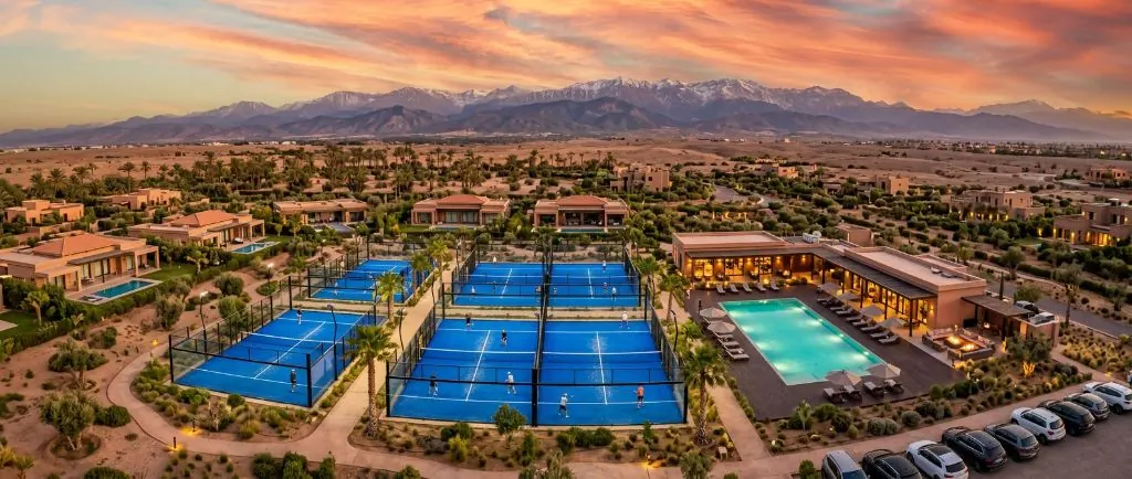 Four blue padel courts at sunset with Atlas Mountains and villas